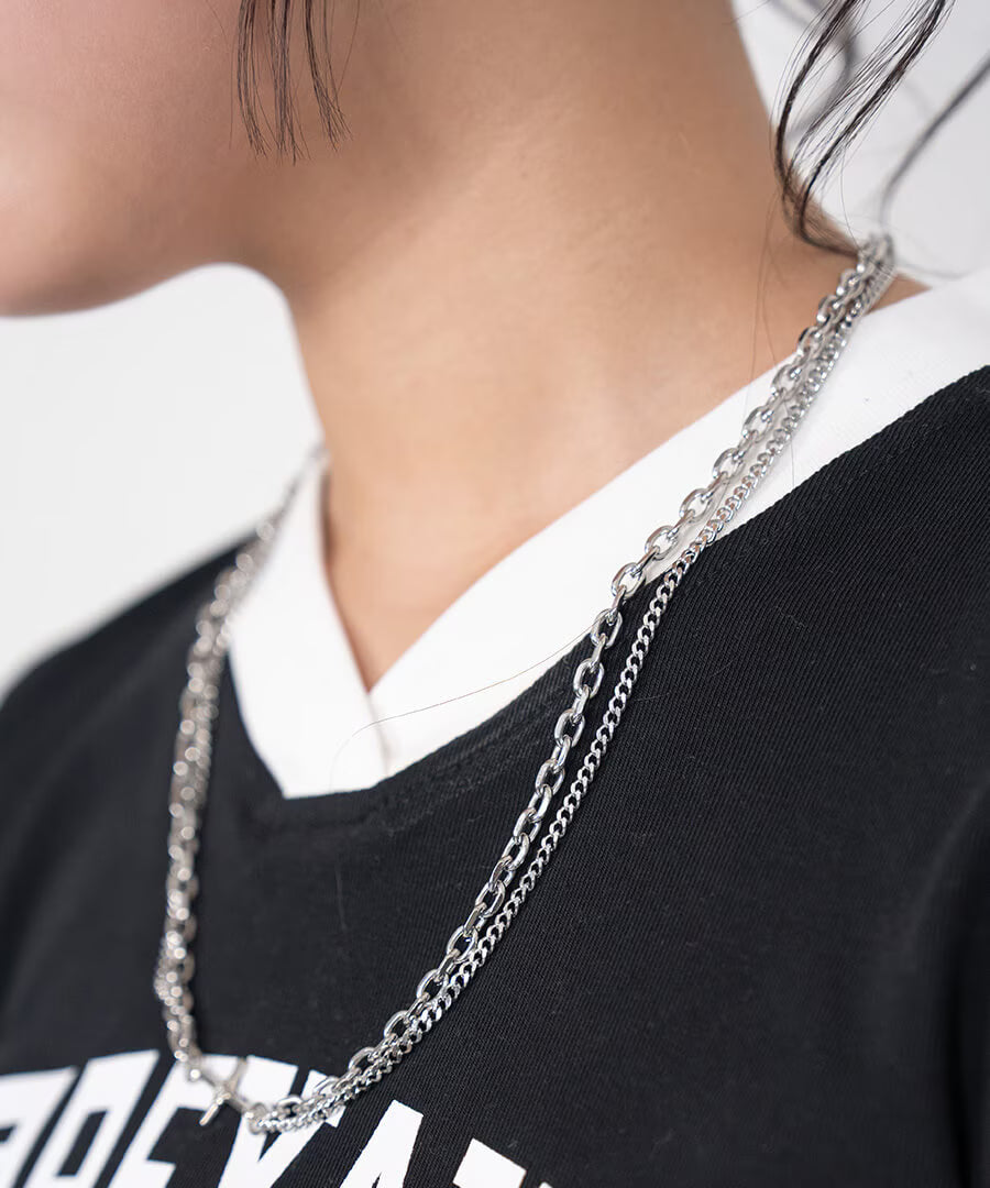 Duality Necklace worn – layered silver Cuban link chain necklace over a black tee