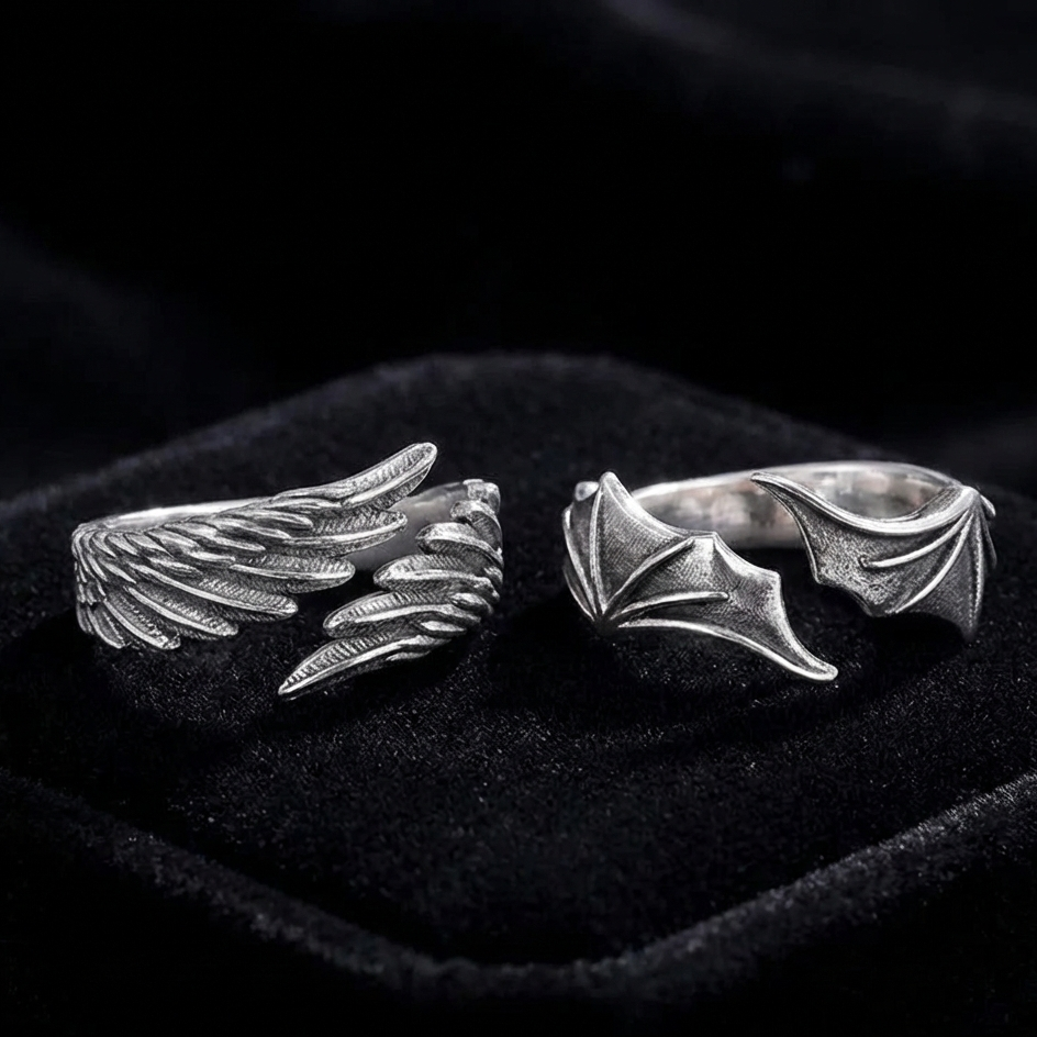 Silver wing-shaped rings on a black velvet surface